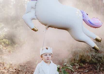 Kind mit großem Einhorn-Folienballon von PartyDeco als besondere Geschenkidee zum Geburtstag