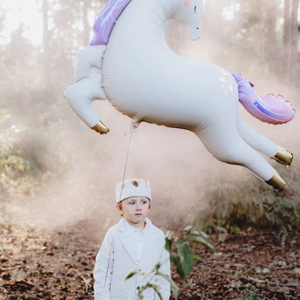 Kind mit großem Einhorn-Folienballon von PartyDeco als besondere Geschenkidee zum Geburtstag