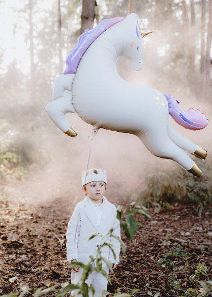 Kind mit großem Einhorn-Folienballon von PartyDeco als besondere Geschenkidee zum Geburtstag