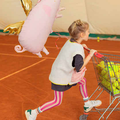 Kind mit schwebendem Folienballon Schweinchen von PartyDeco als Glücksbringer