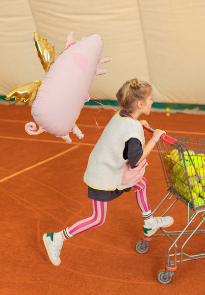 Kind mit schwebendem Folienballon Schweinchen von PartyDeco als Glücksbringer