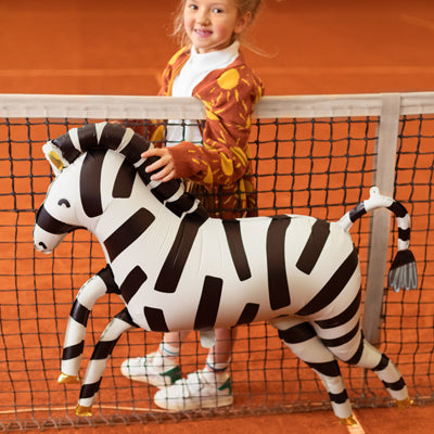 Kind mit XXL Zebra-Folienballon von PartyDeco auf einem Tennisplatz