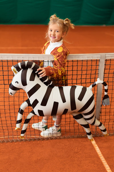 Kind mit XXL Zebra-Folienballon von PartyDeco auf einem Tennisplatz